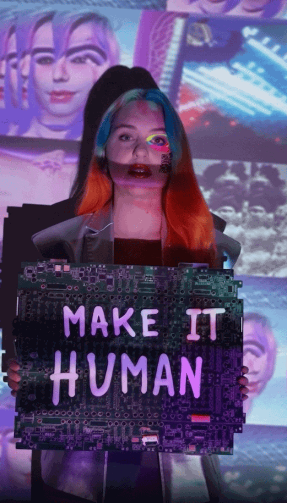 Portrait, a person holding a circuit-board sign that reads MAKE IT HUMAN